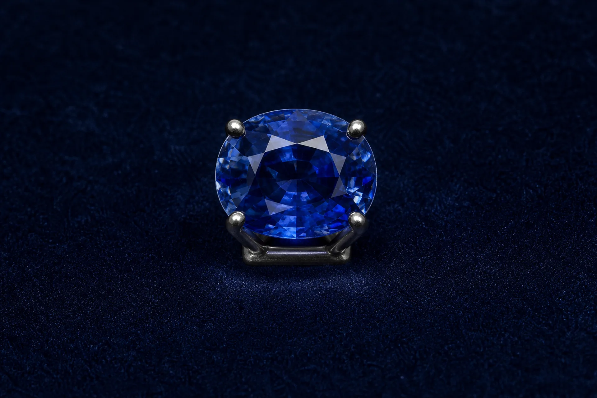 Natural oval blue sapphire held in a dark platinum display setting