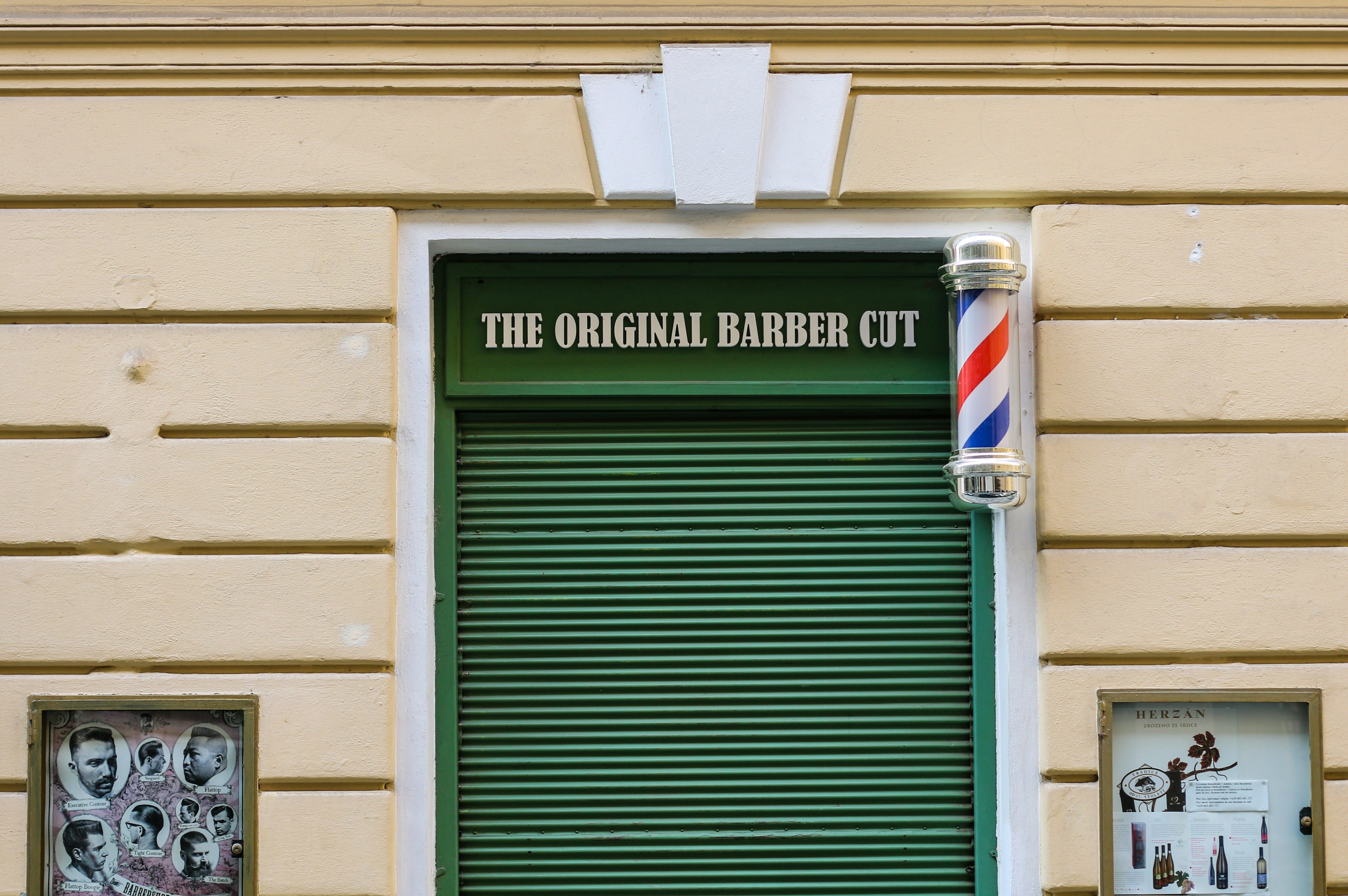Classic barber shop storefront with a barber pole and window signage