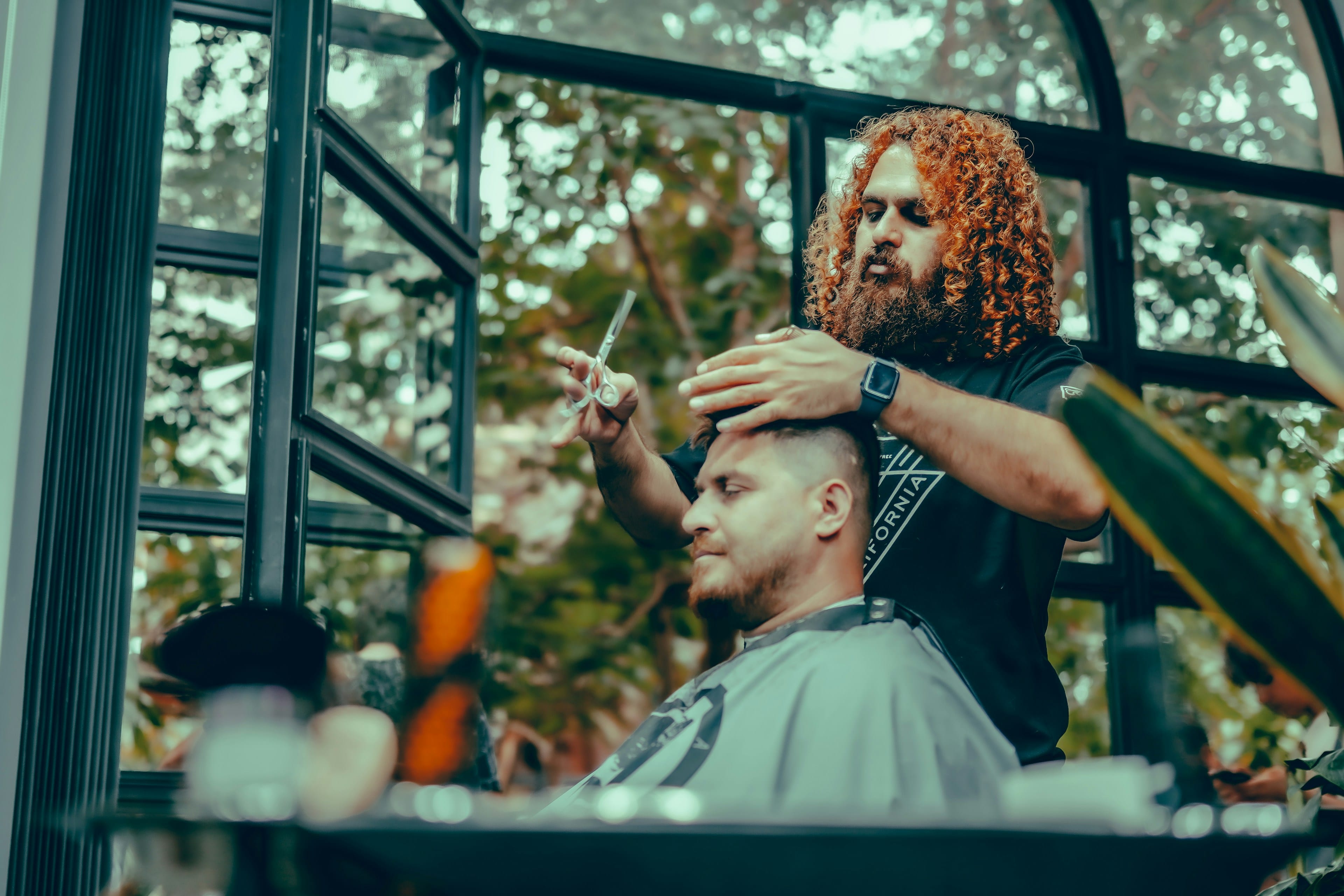 Barber cutting a client's hair in a warm atmospheric shop