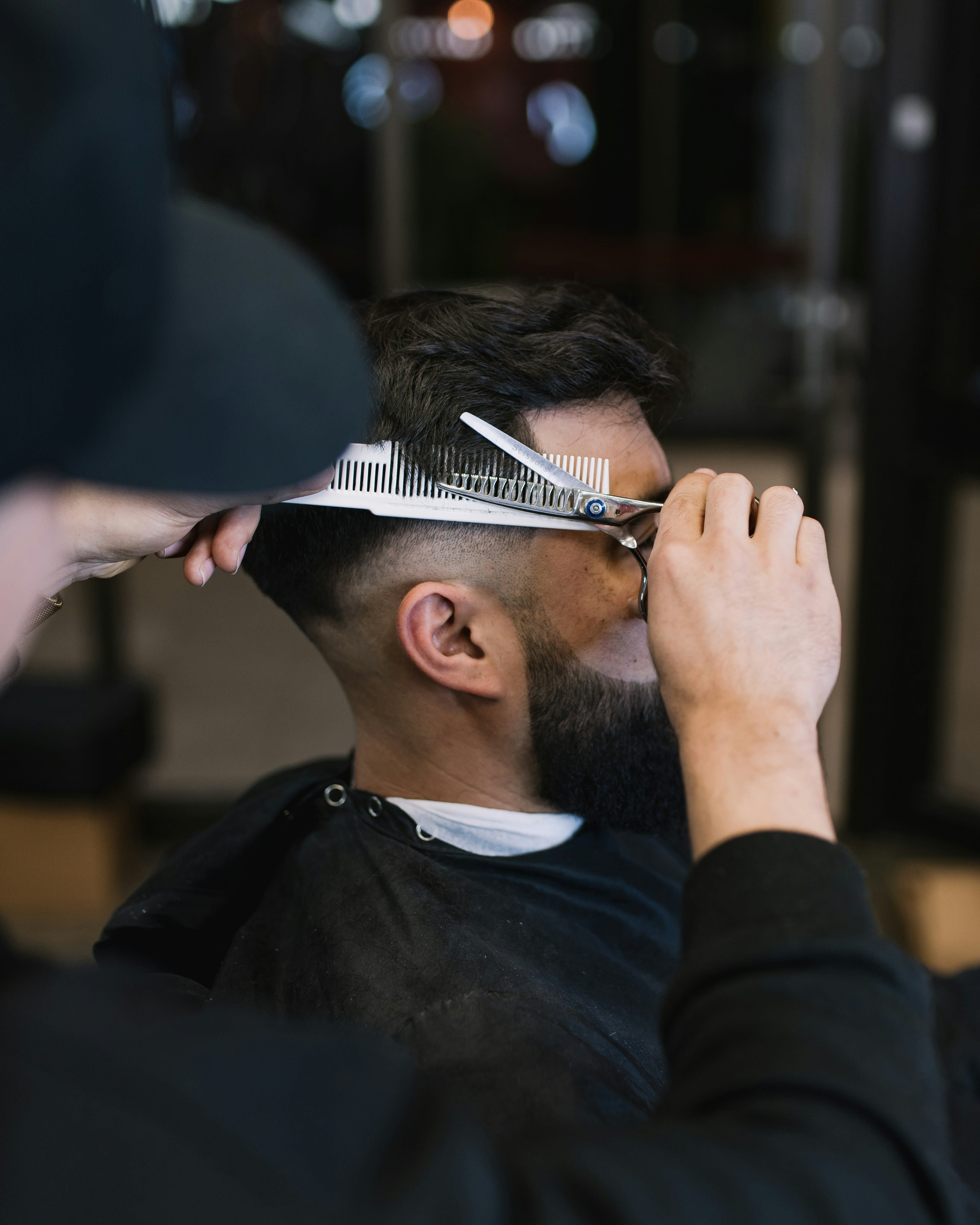Barber cutting hair with scissors in a classic shop