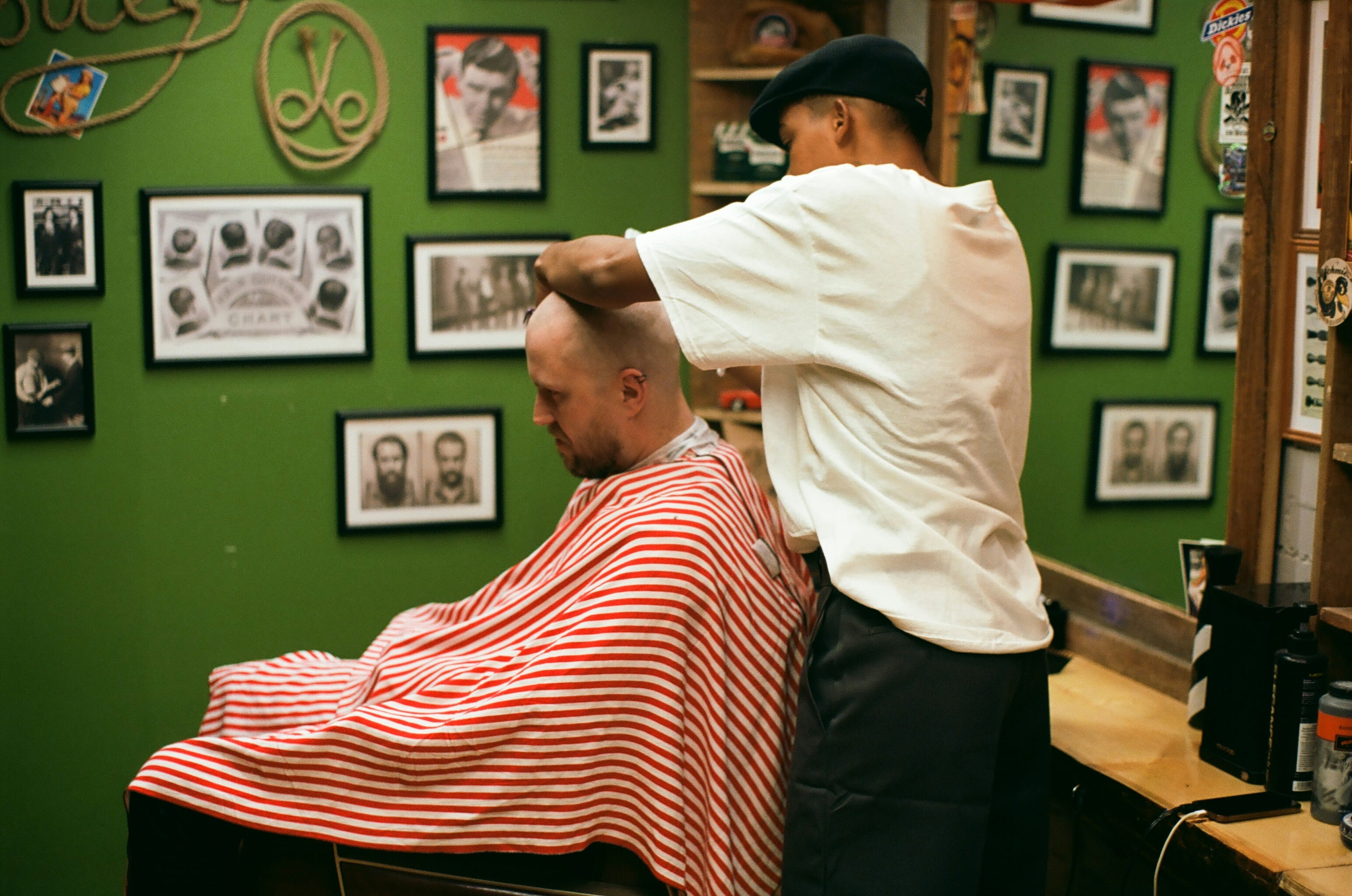 Man getting a haircut in a modern barbershop with a green wall